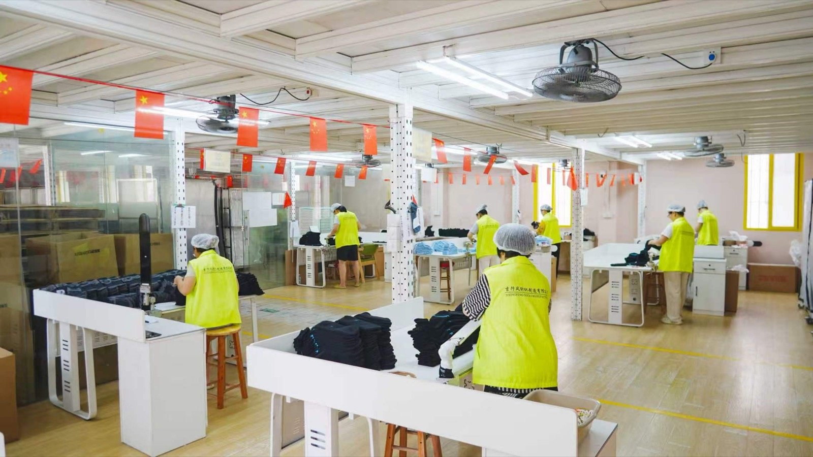 Workers sort and stack dark socks at finishing tables.
